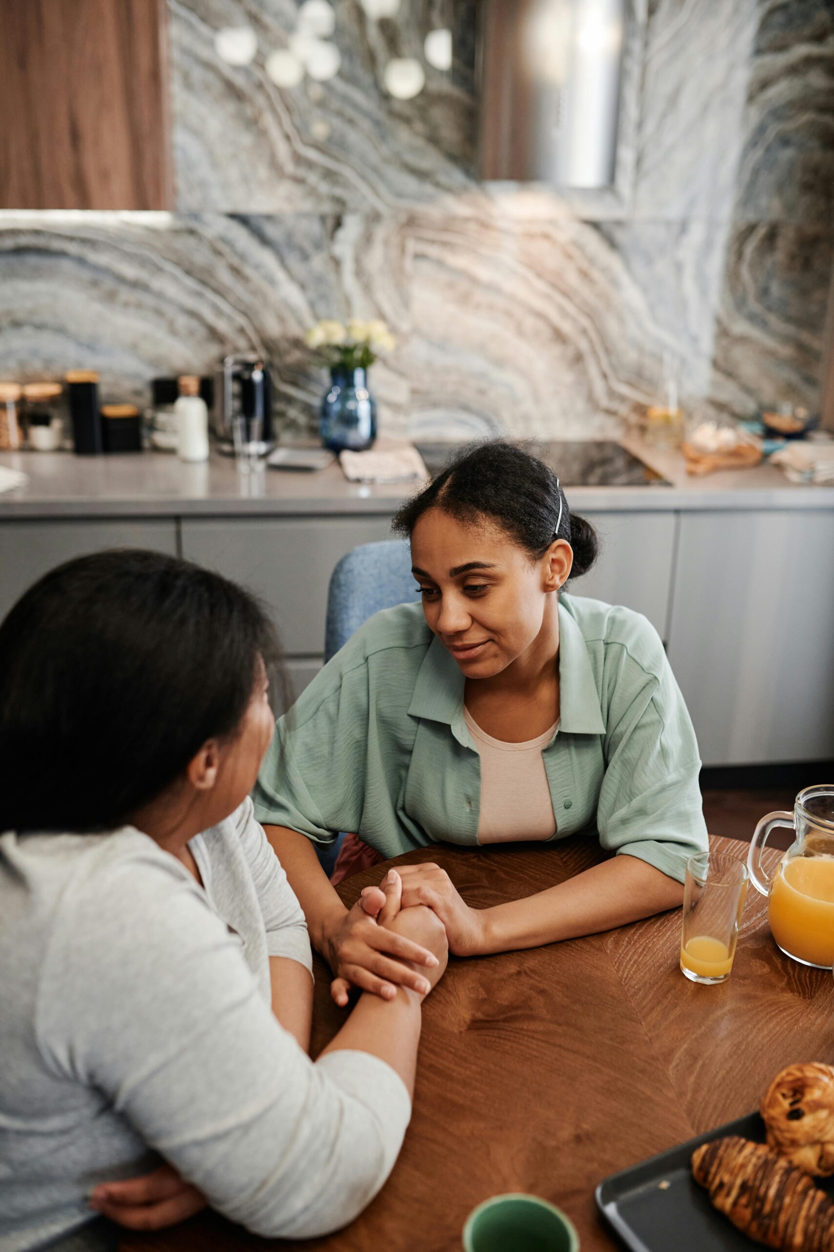 A loving couple holds hands and shares an intimate moment at a kitchen table indoors.